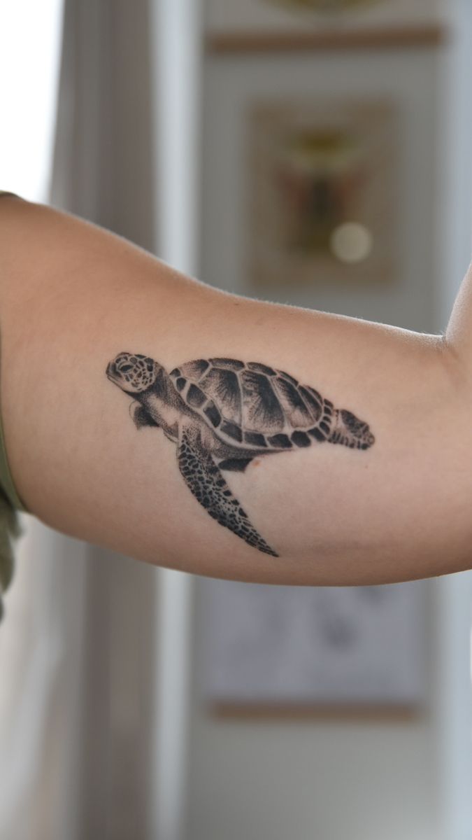 a woman's arm with a tattoo of a turtle on the inside of it