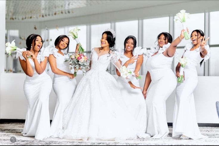 a group of women standing next to each other holding bouquets in front of them