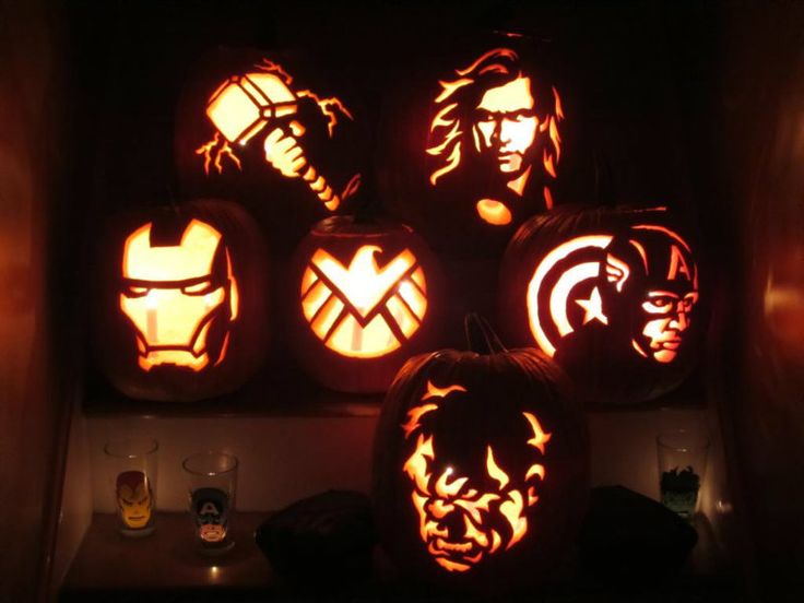 pumpkins carved to look like captain america and iron man are displayed in the dark