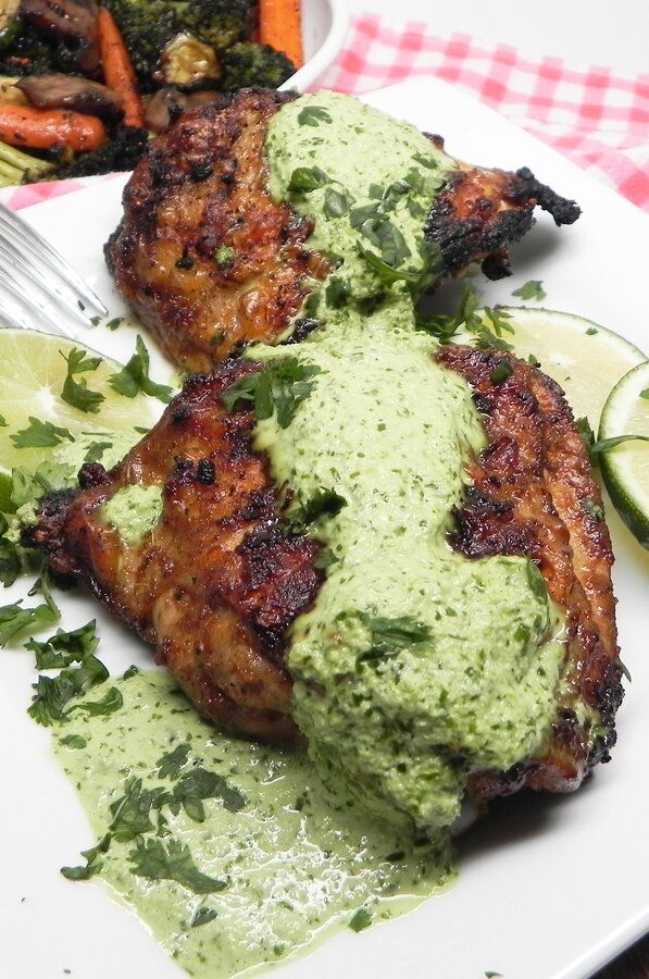 two pieces of meat covered in green sauce and garnished with cilantro