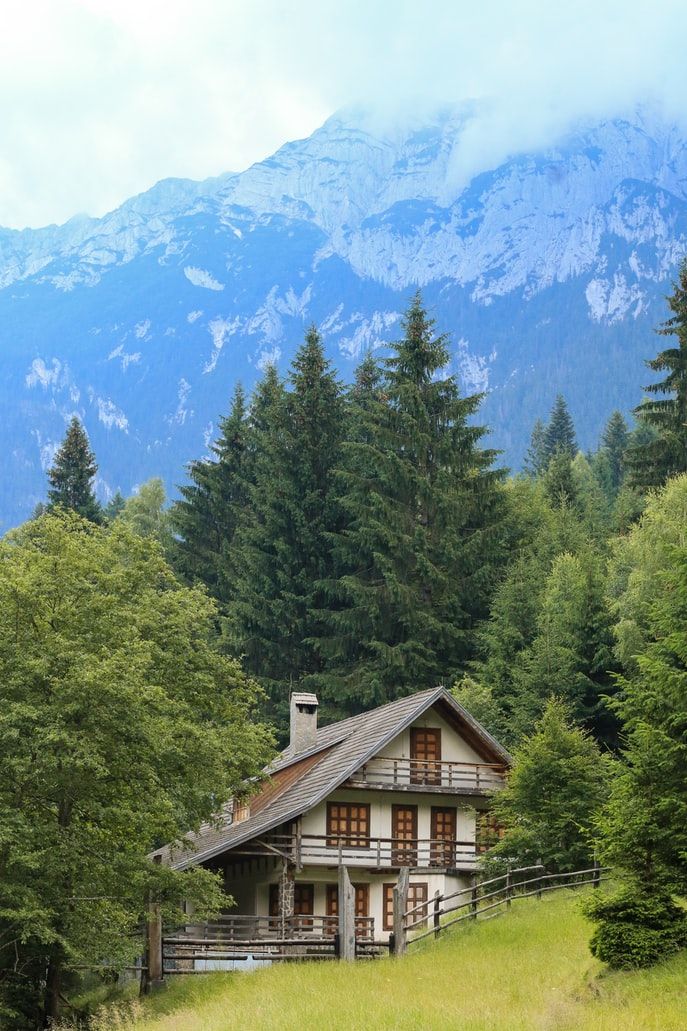 a house in the woods with mountains in the background