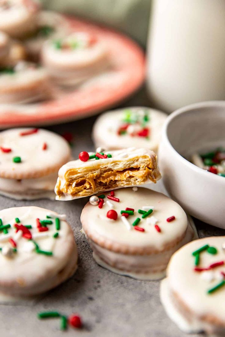 cookies with white frosting and sprinkles on a table