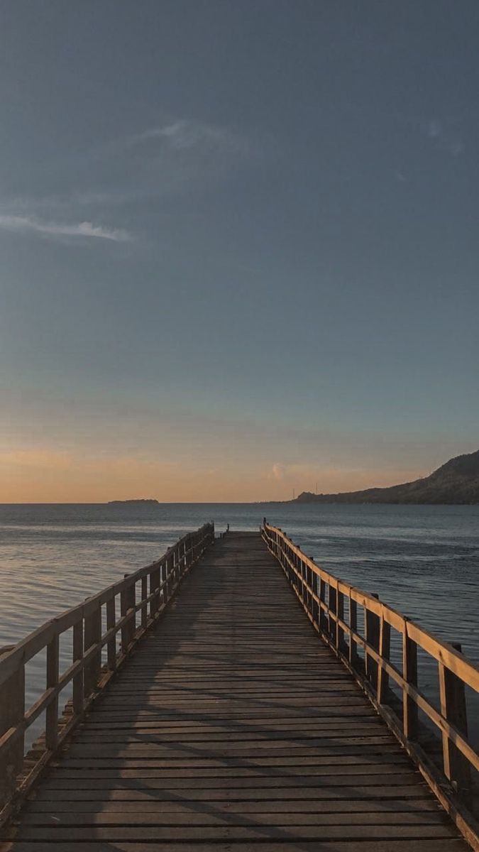 a long wooden pier stretching out into the ocean