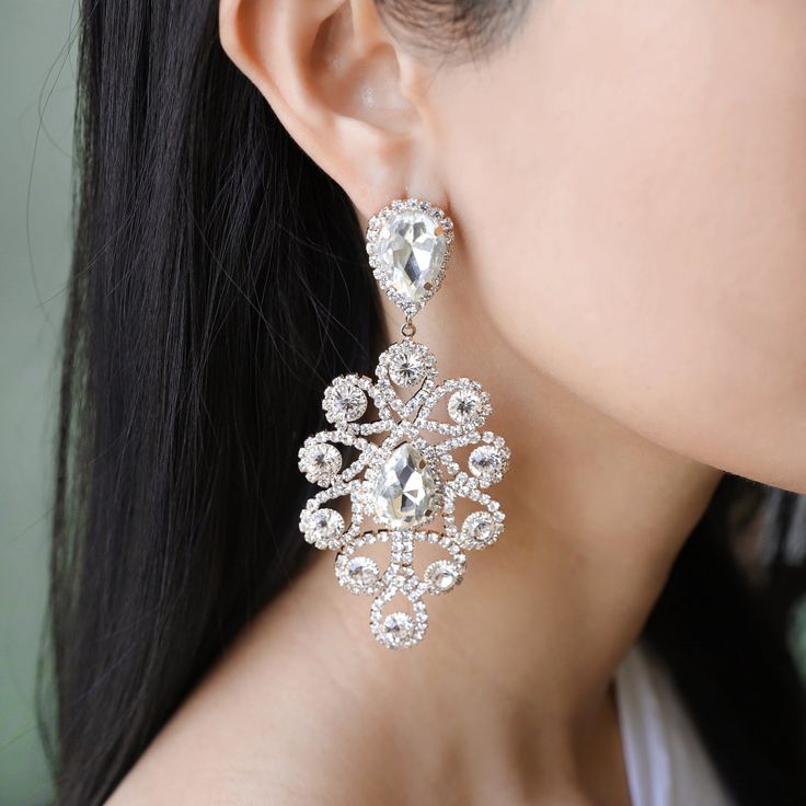 With these sparkling masterpiece jewelry on your ears, you'll light up the whole room like the sun rising over a skylight. Shoulder length and lightweight, wear these stunning chandelier statement earrings with a casual white tee for that extra oomph of bling or an off the shoulder dress/blouse to catch anyone's eye. Size• Post backing earrings.• Length: 3.25 in (8.26 cm)• Width: 1.75 in (4.45 cm) QualityLarge iridescent shiny rhinestone gems surrounded by mini stones in a teardrop chandelier de Crystal Drop Chandelier Earrings, White Dangle Chandelier Earrings With Cubic Zirconia, Glamorous White Chandelier Earrings With Sparkling Stones, Glamorous White Cubic Zirconia Chandelier Earrings, Glamorous White Dangle Teardrop Earrings, Dazzling White Crystal Earrings, White Crystal Teardrop Earrings With Sparkle, White Crystal Teardrop Earrings With Sparkling Detail, Glamorous White Teardrop Crystal Earrings