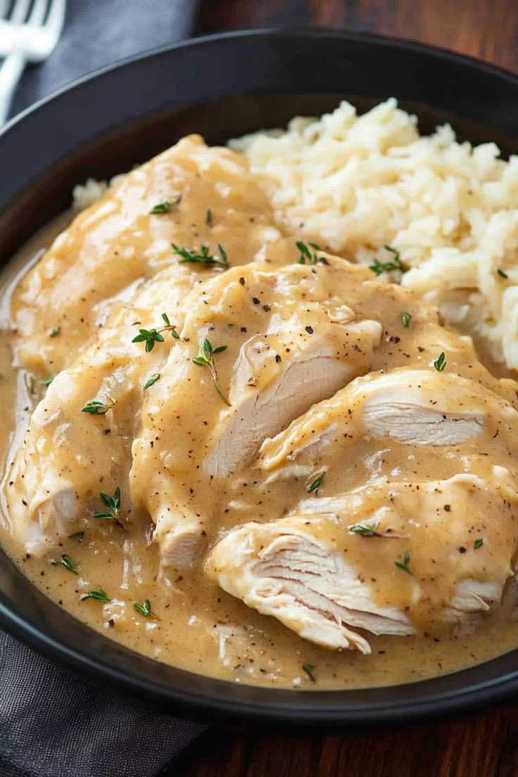 chicken and gravy served with mashed potatoes in a black bowl on a wooden table