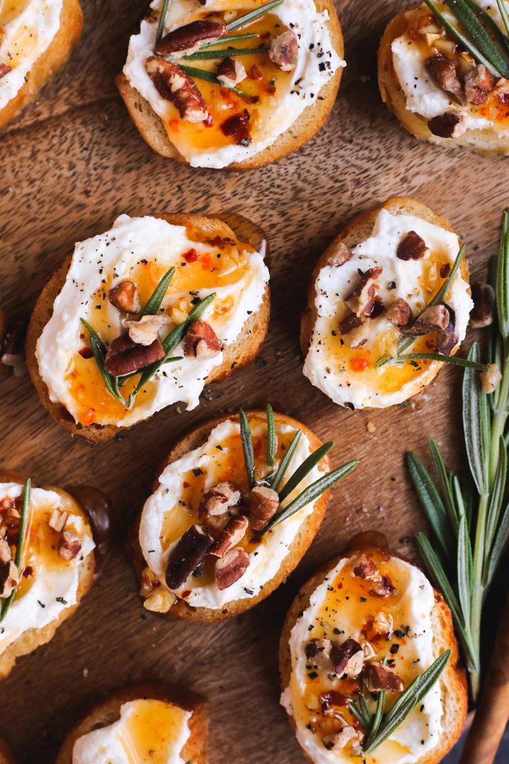 small appetizers are arranged on a wooden platter with rosemary sprigs