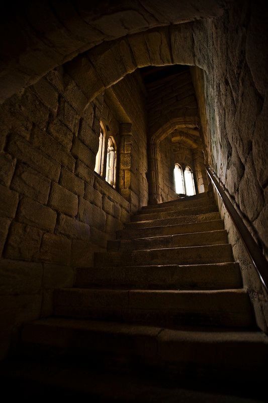 the stairs lead up to an old stone building with light coming in from two windows