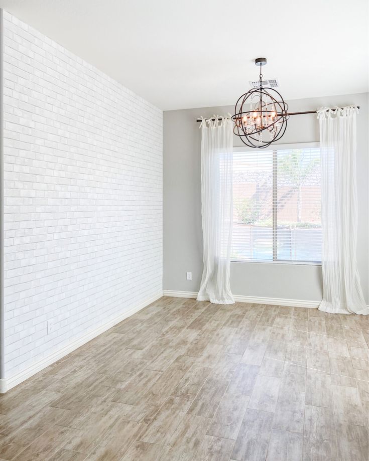 an empty living room with white brick walls and wood flooring is seen in this image