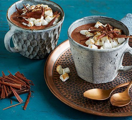 two mugs filled with hot chocolate and marshmallows on a copper plate