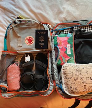 an open suitcase sitting on top of a bed filled with clothing and accessories, including shoes