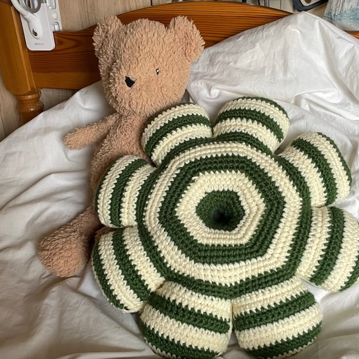 there is a teddy bear laying on the bed next to two crocheted circles