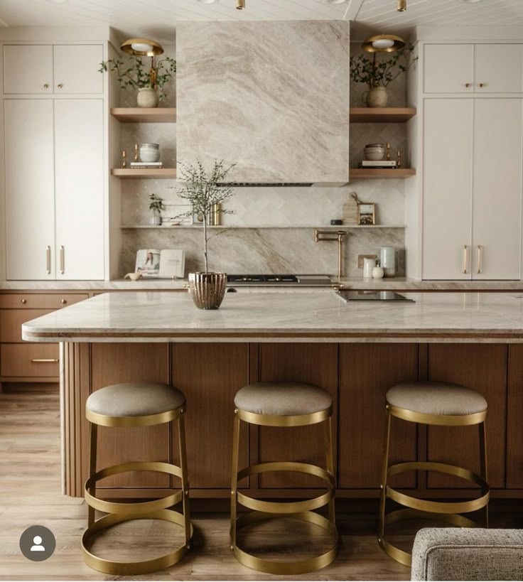 a kitchen with marble counter tops and gold bar stools in front of an island