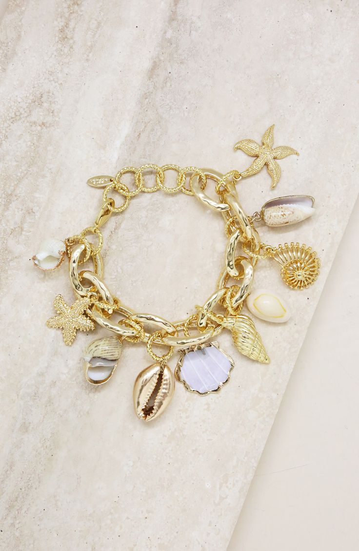 Natural and sculpted shell charms dance along this handcrafted bracelet in 18-karat-gold plate. 7" length; 1 1/2" extender Lobster clasp closure 18k-gold plate/shell Imported Ocean Bracelet, Surf Jewelry, Mermaid Tears, Bracelet Elegant, Crystal Hoop Earrings, Gold Charm Bracelet, Handcrafted Bracelets, Shell Bracelet, Gold Plated Bracelets