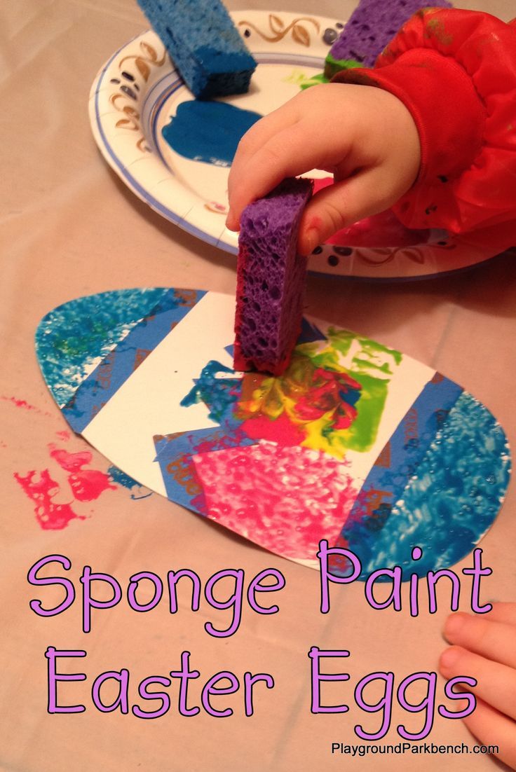 a child's hands painting an easter egg with sponge paint