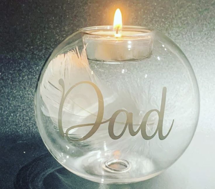 a glass candle holder with the word dad written on it