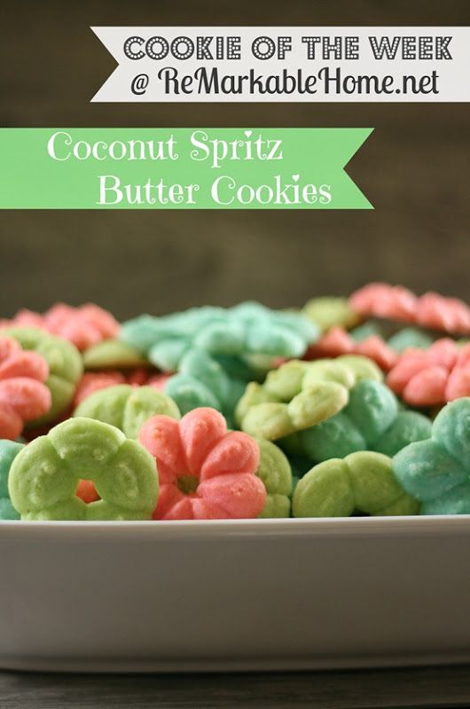 a white bowl filled with cookies covered in green and pink frosting on top of a wooden table