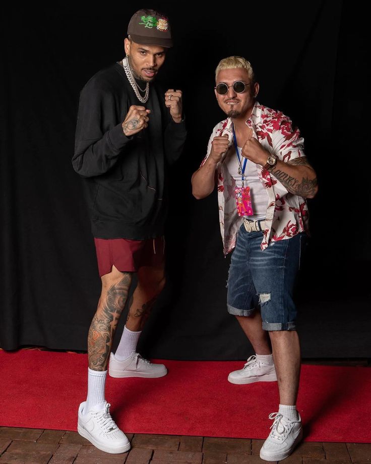 two men standing next to each other in front of a red carpet and black backdrop