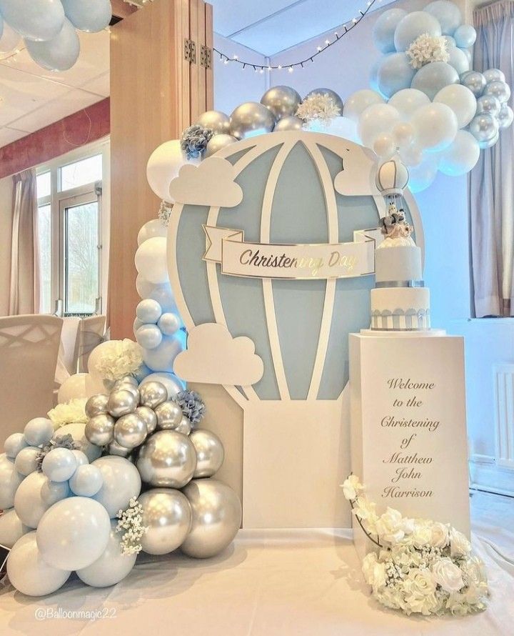 balloons and decorations are on the table for a baby's first birthday party in blue, white and silver