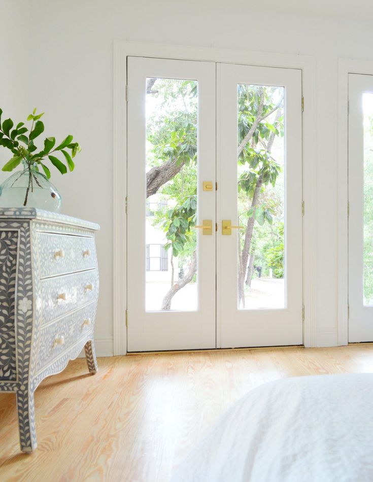 a white bed sitting next to two french doors