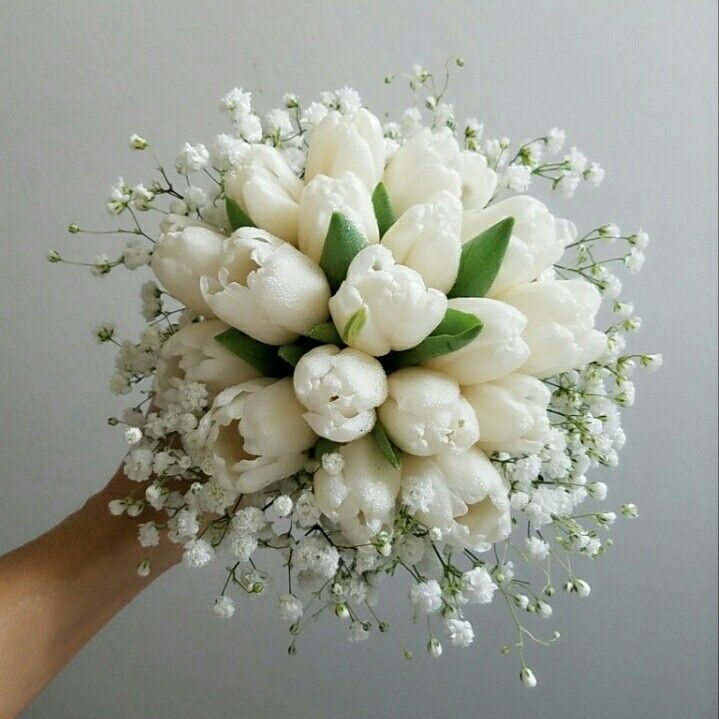 a bridal bouquet with white tulips and baby's breath in it