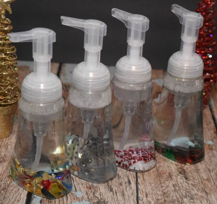 four bottles filled with liquid sitting on top of a wooden table next to a christmas tree