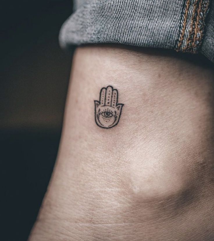 a small hamsa tattoo on the side of a woman's stomach, with an eye