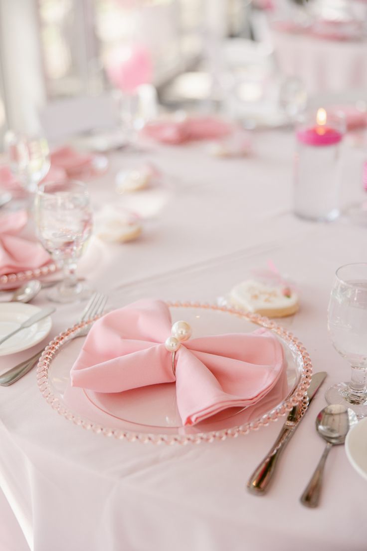 the table is set with pink napkins and silverware