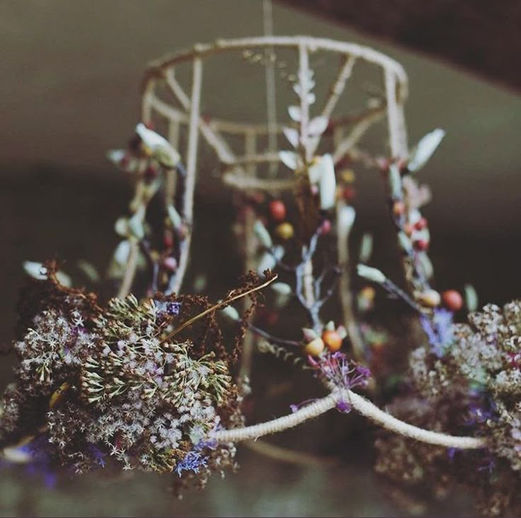 an arrangement of dried flowers in front of a metal object with strings attached to it