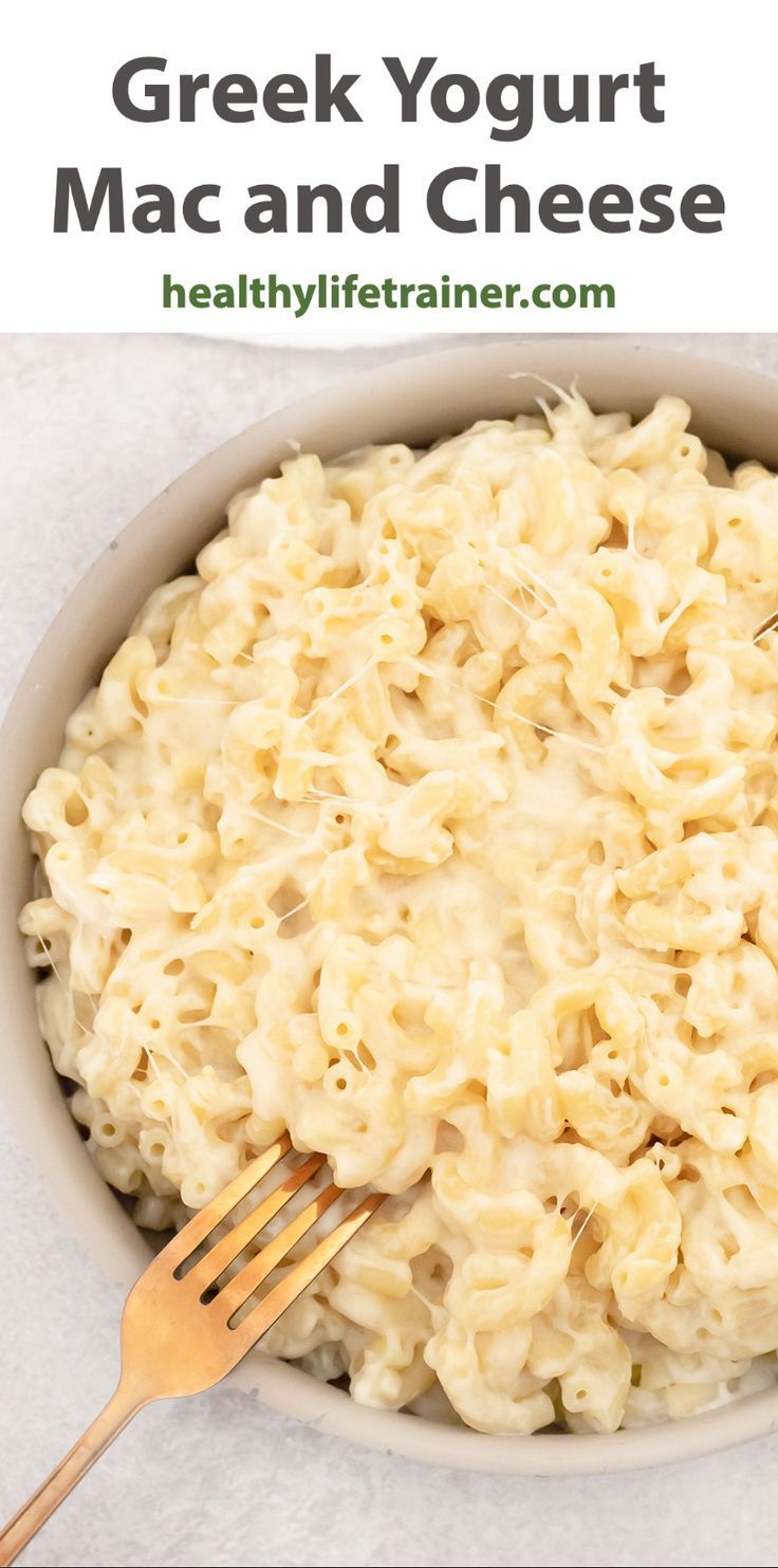 a white bowl filled with macaroni and cheese next to a wooden fork on top of it