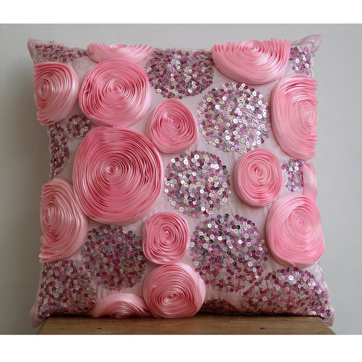 a pink pillow with sequins and flowers on the front is sitting on a table