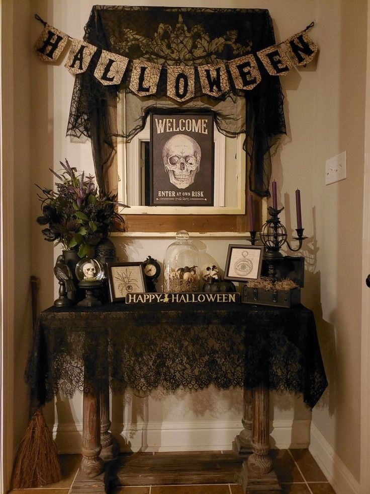 a decorated entry way with halloween decorations on the table and welcome sign hanging above it