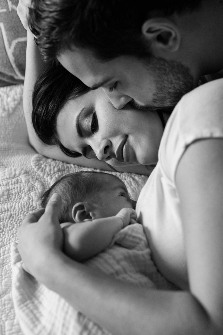 a man and woman are cuddling while holding a baby