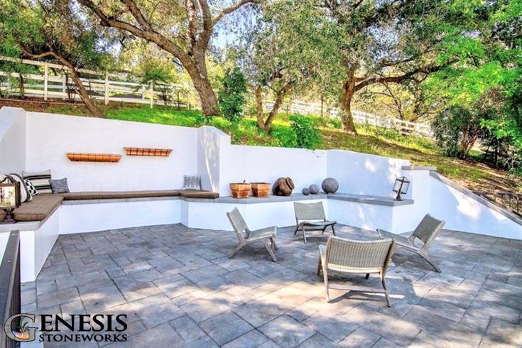 an outdoor patio with tables and chairs on it, surrounded by trees in the background