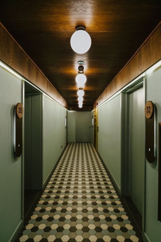 an empty hallway with checkered flooring and two lights on the ceiling above them