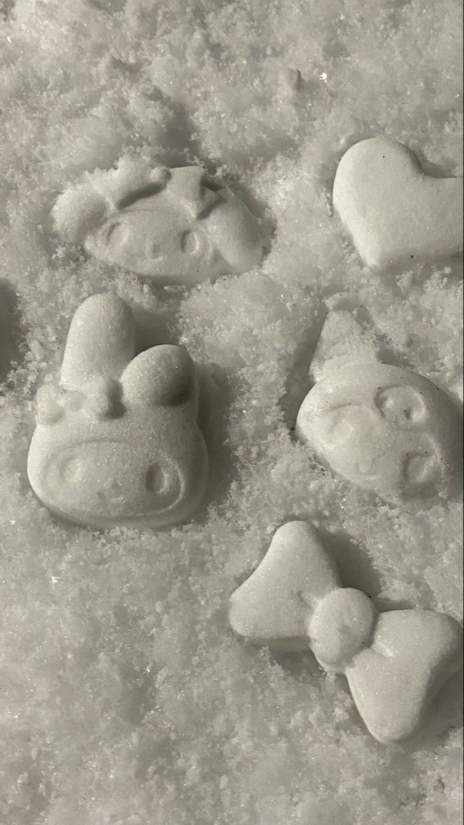 four heart shaped cookies are sitting in the middle of some sugary icing on top of snow