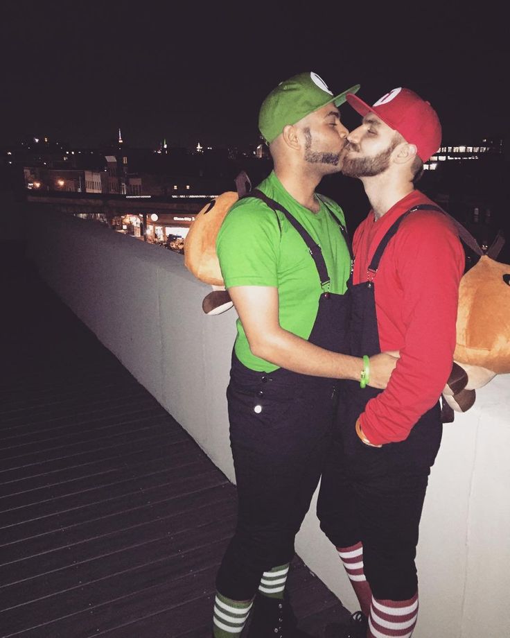 two people standing next to each other on a bridge at night with one person kissing the other