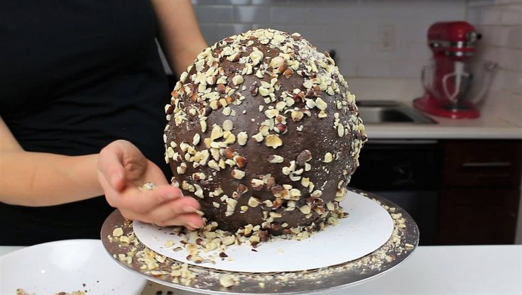 a person is decorating a chocolate cake with nuts