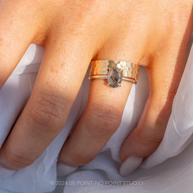 a woman's hand wearing a gold ring with an oval shaped diamond on it