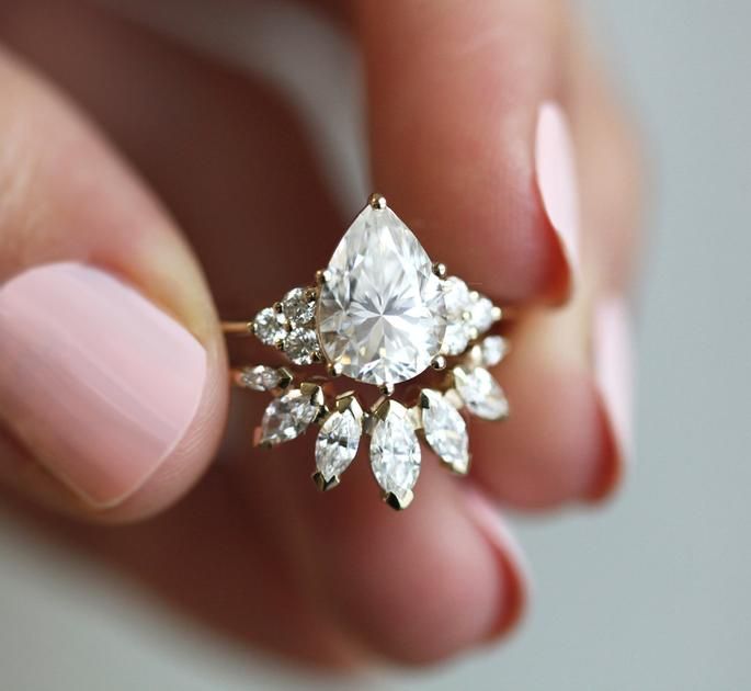 a close up of a person holding a ring with diamonds on it's fingers