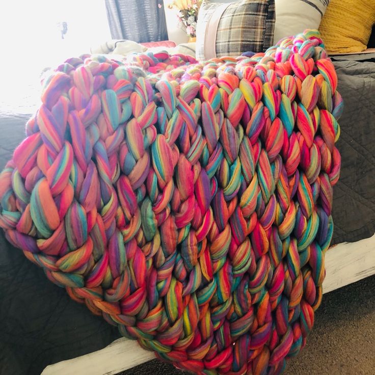 a large multicolored pillow sitting on top of a bed