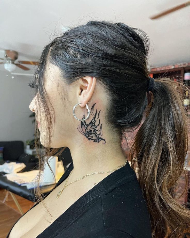 a woman with a black dragon tattoo on her neck and behind her ear is a pair of hoop earrings