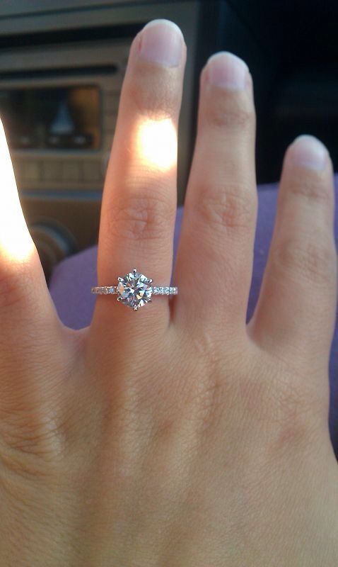 a woman's hand with a diamond ring on top of her finger in the car