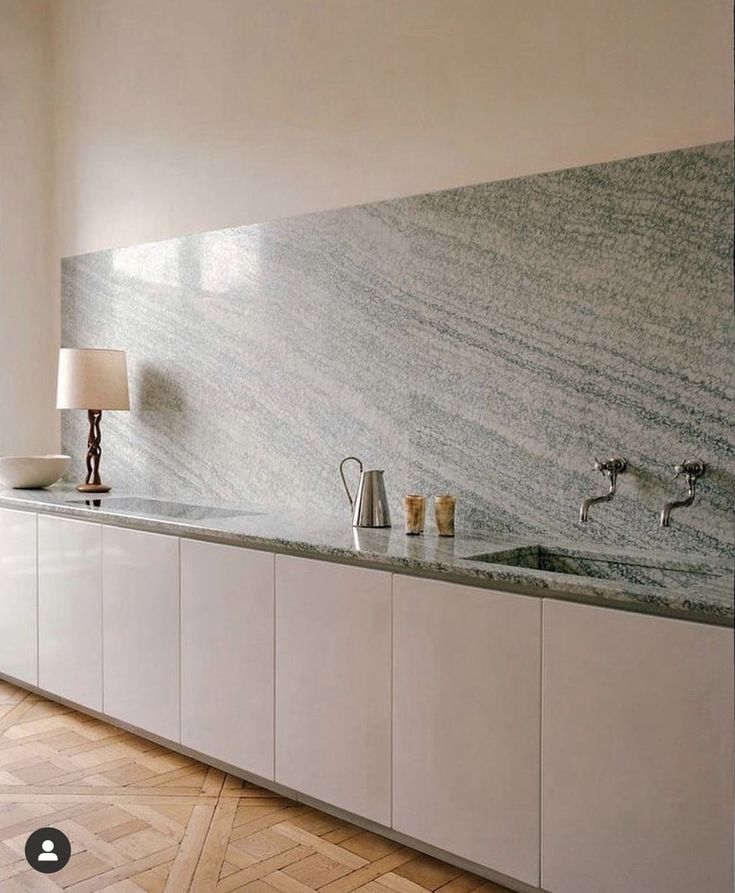 a kitchen with white cabinets and marble counter tops in the middle of an open floor plan