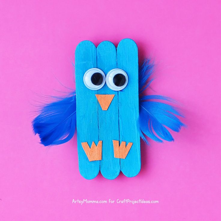 a blue bird made out of popsicle sticks with googly eyes on pink background