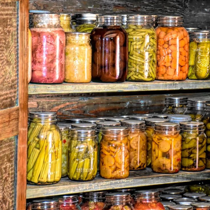 jars filled with pickles and beans sitting on top of a shelf next to each other