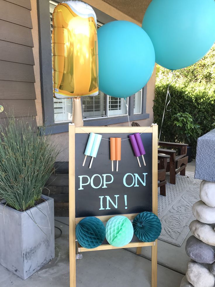 a sign that says pop on in front of some balloons and yarn ball holders outside