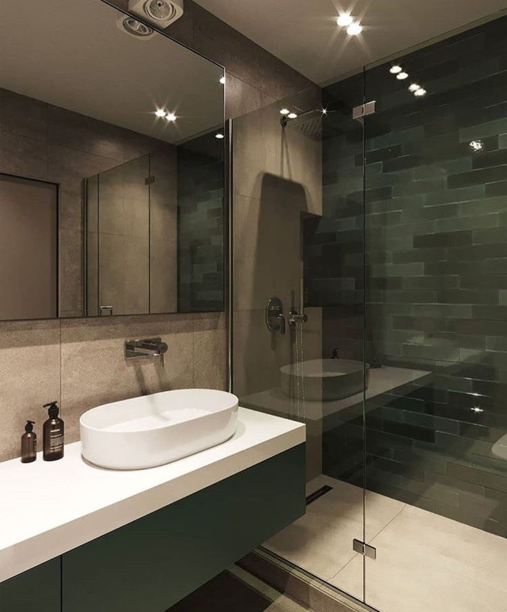 a white sink sitting under a bathroom mirror next to a walk in shower and toilet