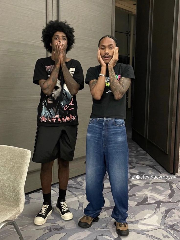 two young men standing next to each other in front of a mirror with their hands together