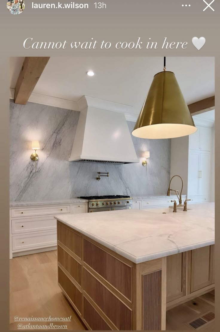 an image of a kitchen with marble countertops and gold pendant lights above the island