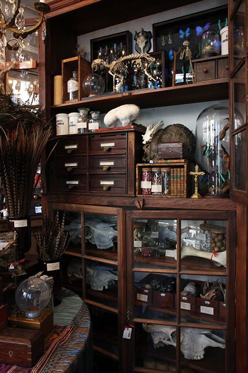 an old wooden shelf with many items on it and a chandelier hanging from the ceiling